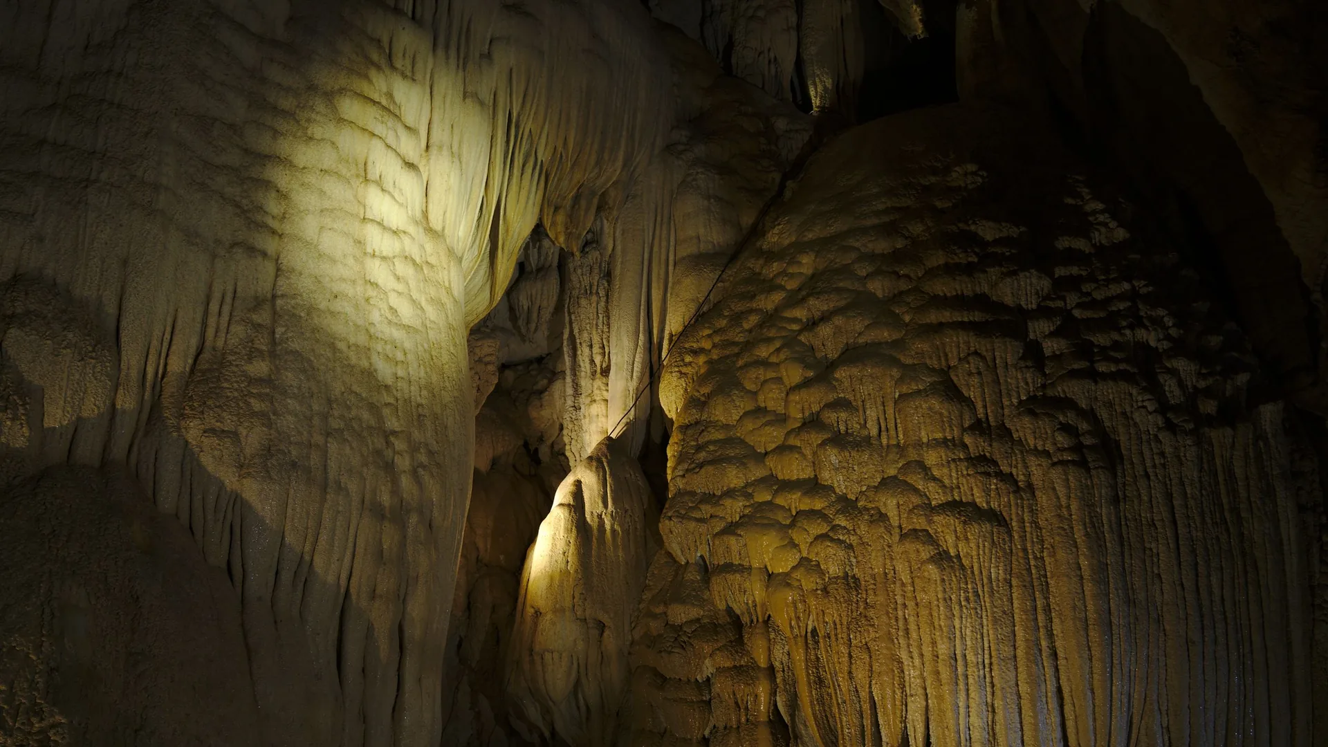 A wooden boat gliding into the illuminated river cavern of Phong Nha Cave in Vietnam